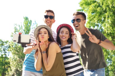 Photo of Group of young people taking selfie with monopod outdoors