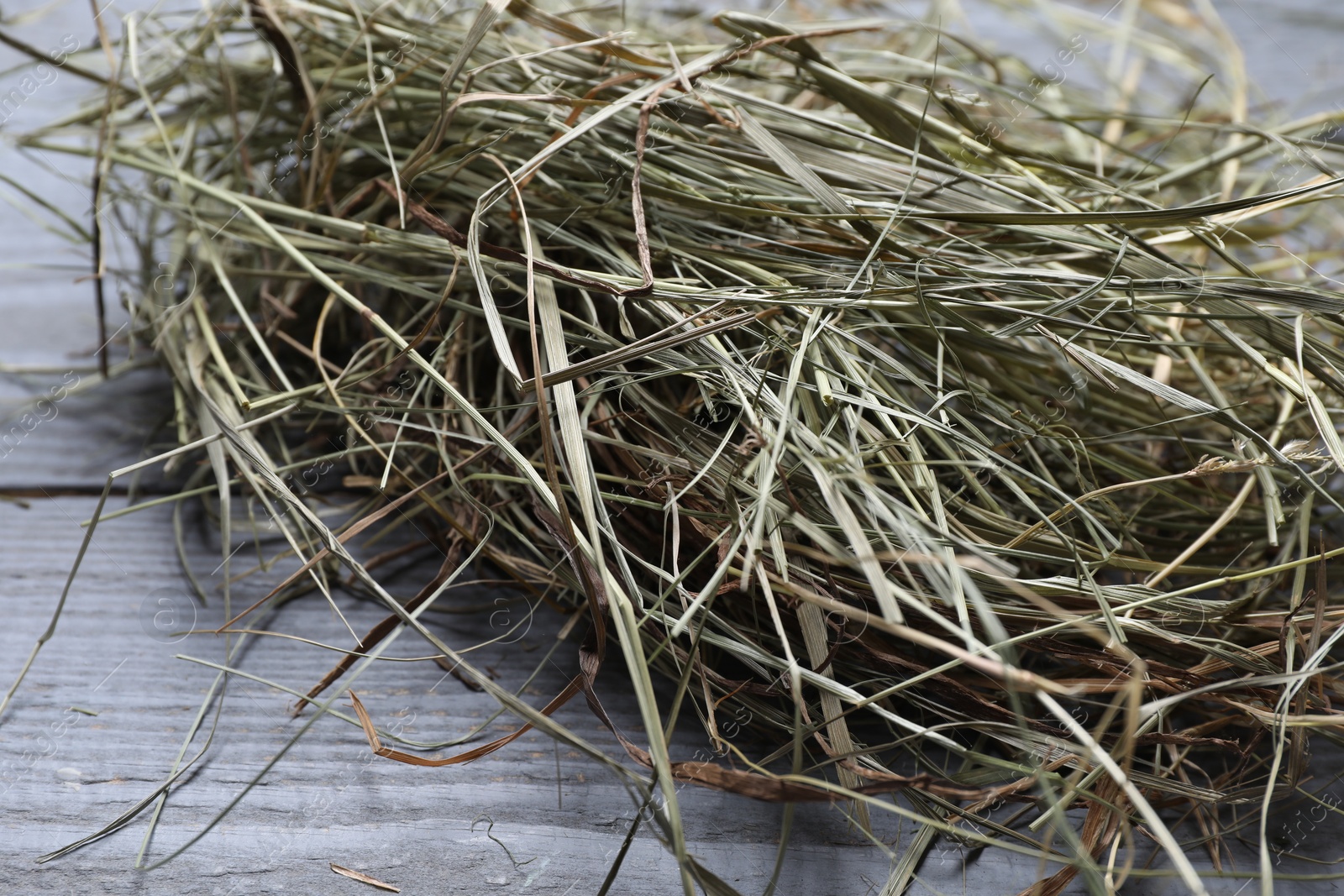 Photo of Heap of dried hay on grey wooden table, closeup