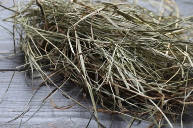 Heap of dried hay on grey wooden table, closeup