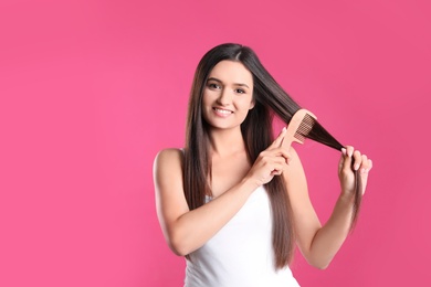 Photo of Beautiful smiling young woman with hair comb on color background