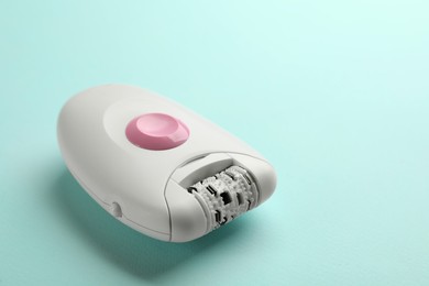 Photo of Modern epilator on turquoise background, space for text