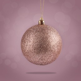 Image of Beautiful glittery Christmas ball hanging on color background