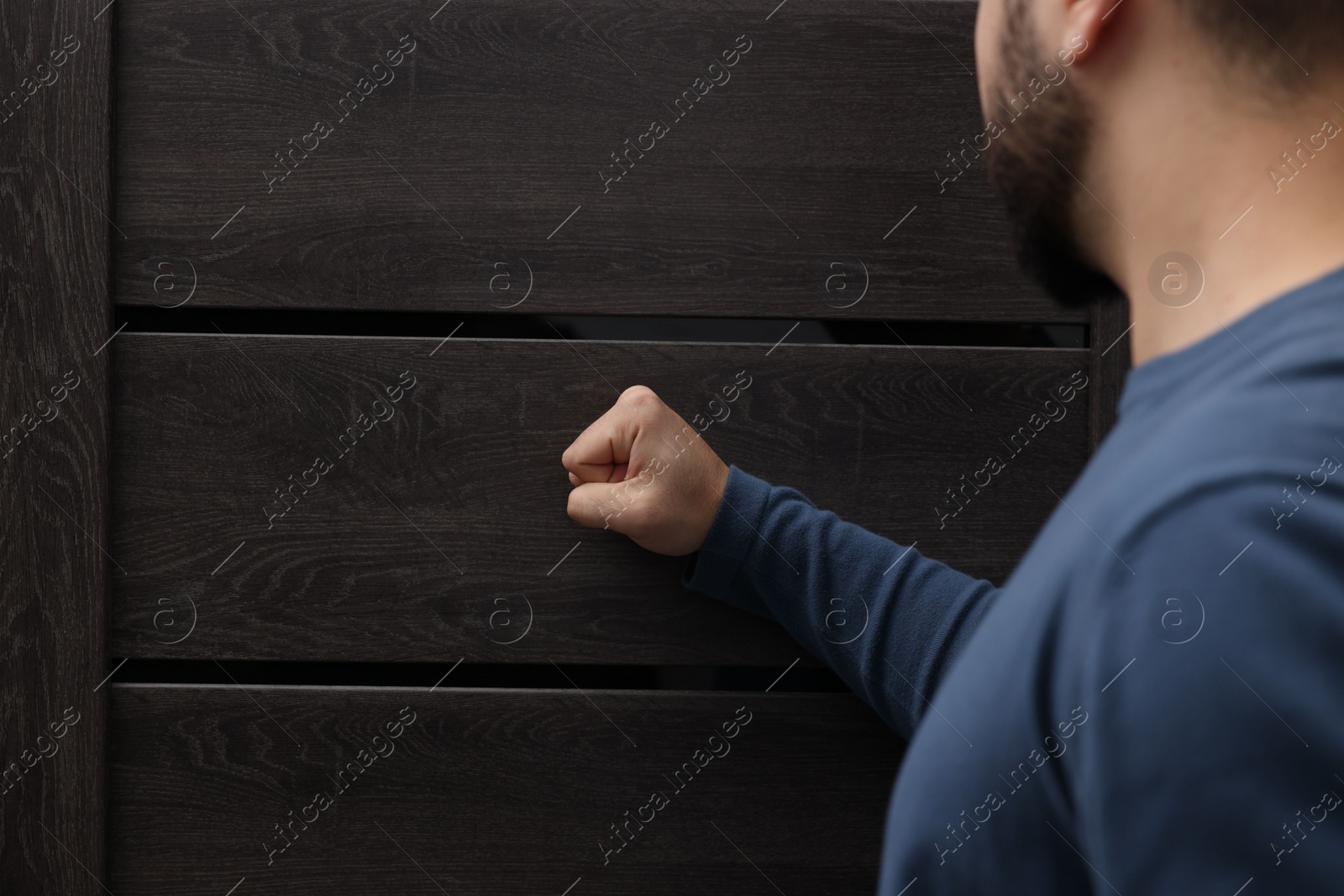 Photo of Collection agent knocking on wooden door, closeup