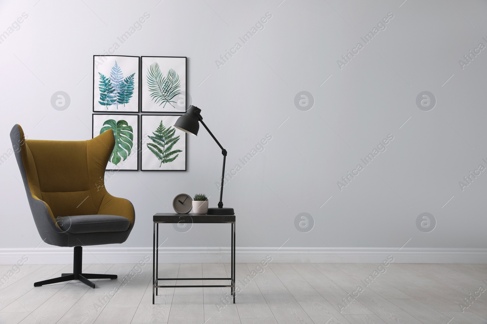 Photo of Stylish room interior with comfortable armchair and paintings of tropical leaves. Space for text