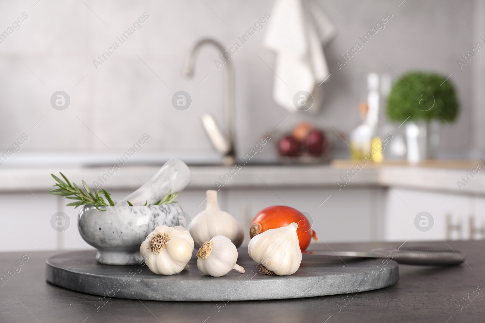 Photo of Fresh raw garlic, onion and rosemary on grey table