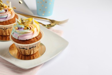 Photo of Plate with cute sweet unicorn cupcakes on white table, space for text