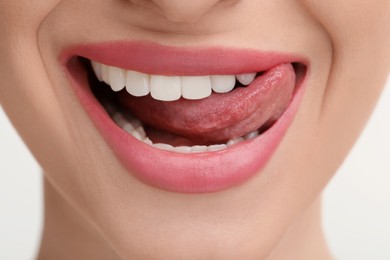 Photo of Young woman licking her teeth on white background, closeup