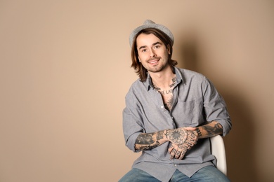Photo of Young man with tattoos on body against beige background
