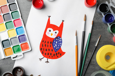 Flat lay composition with child's painting of owl on grey table