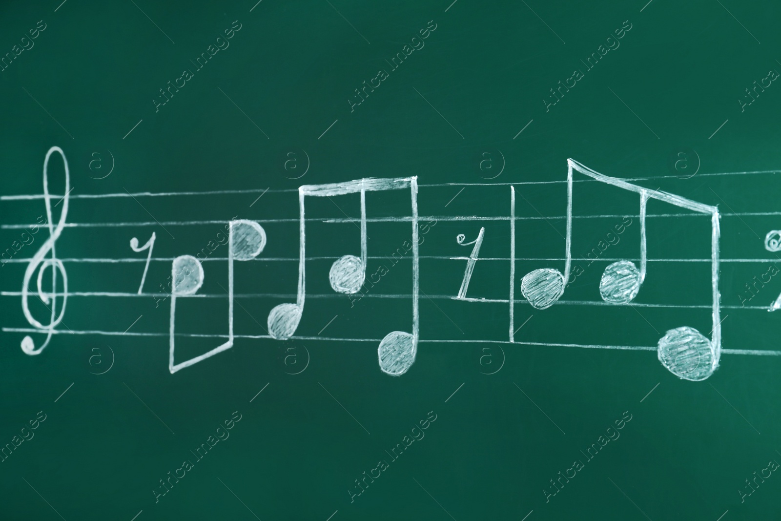 Photo of Music staff with treble clef and notes written on chalkboard