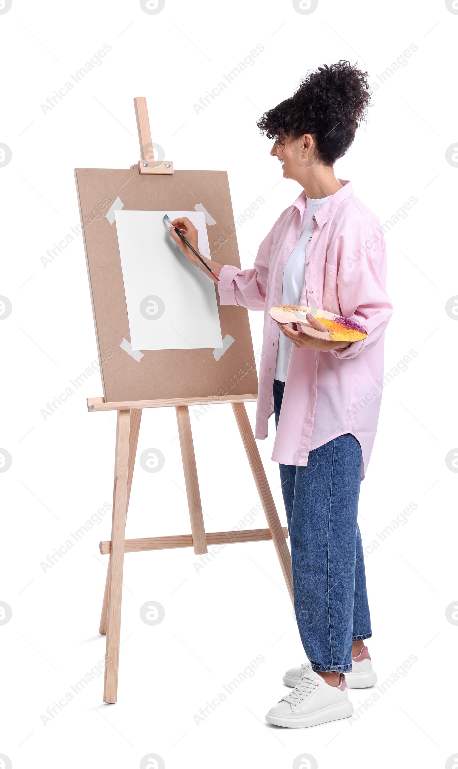 Photo of Young woman painting on easel with paper against white background