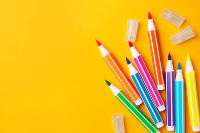 Photo of Many bright markers on yellow background, flat lay. Space for text