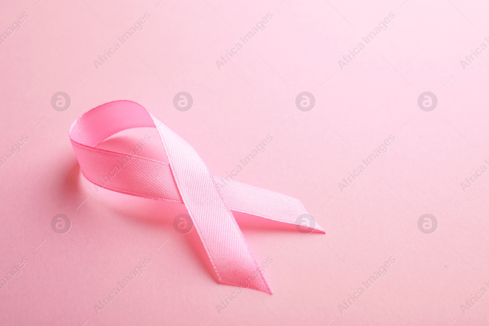 Photo of Pink ribbon on color background, space for text. Breast cancer awareness concept