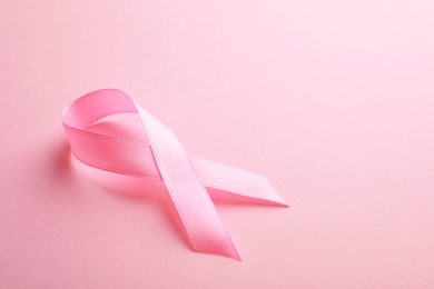 Photo of Pink ribbon on color background, space for text. Breast cancer awareness concept
