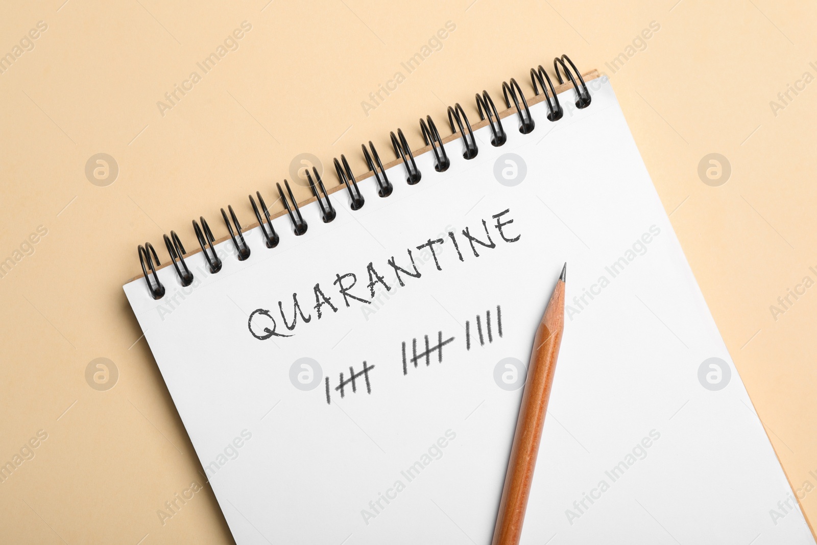 Image of Open notebook and pencil on beige background, top view. Counting days of quarantine during coronavirus outbreak