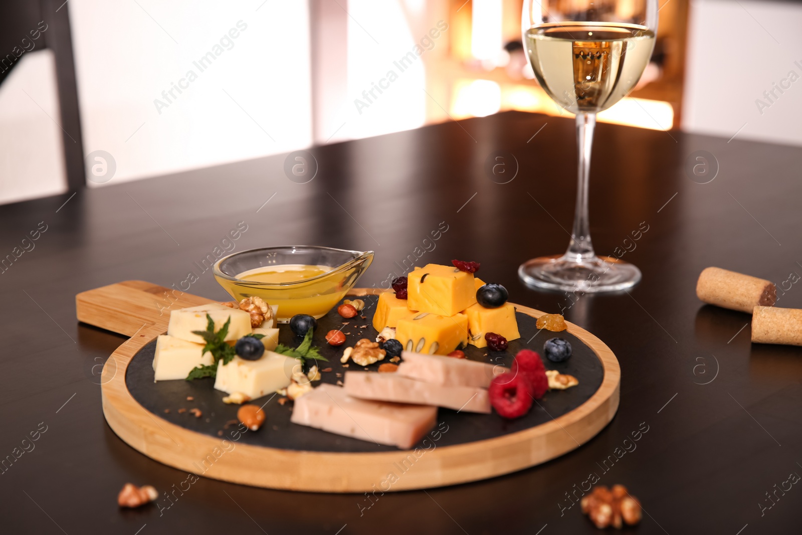 Photo of Different types of delicious cheeses, berries and honey on table