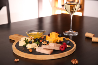 Photo of Different types of delicious cheeses, berries and honey on table