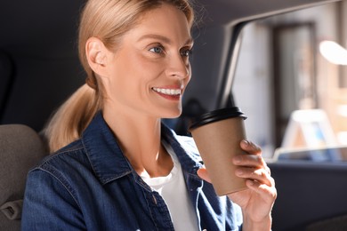 Photo of Coffee to go. Happy woman with paper cup of drink in car