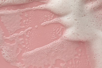 White washing foam on pale pink background, top view