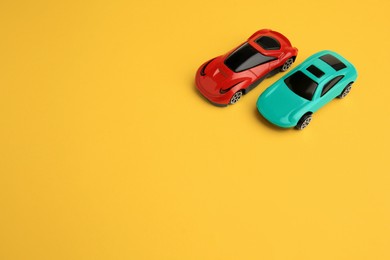 Photo of Bright cars on yellow background, space for text. Children`s toys