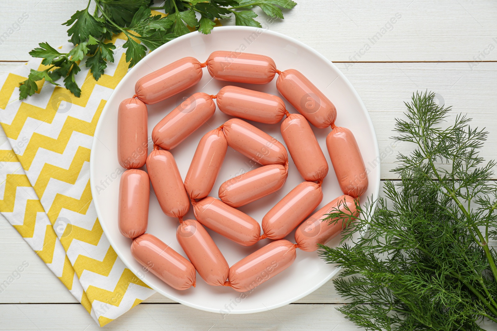 Photo of Delicious sausages, dill and parsley on white wooden table, flat lay