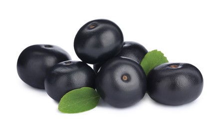 Pile of fresh ripe acai berries and green leaves on white background