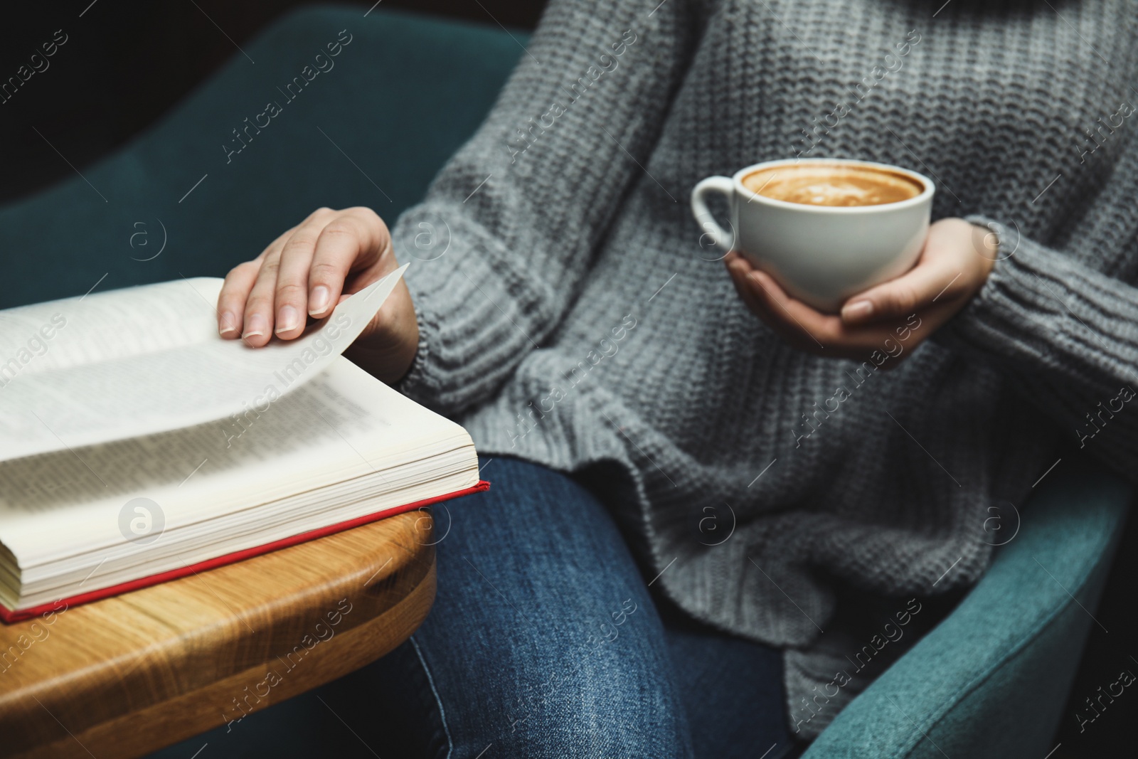 Photo of Woman with cup of coffee reading book at home, closeup