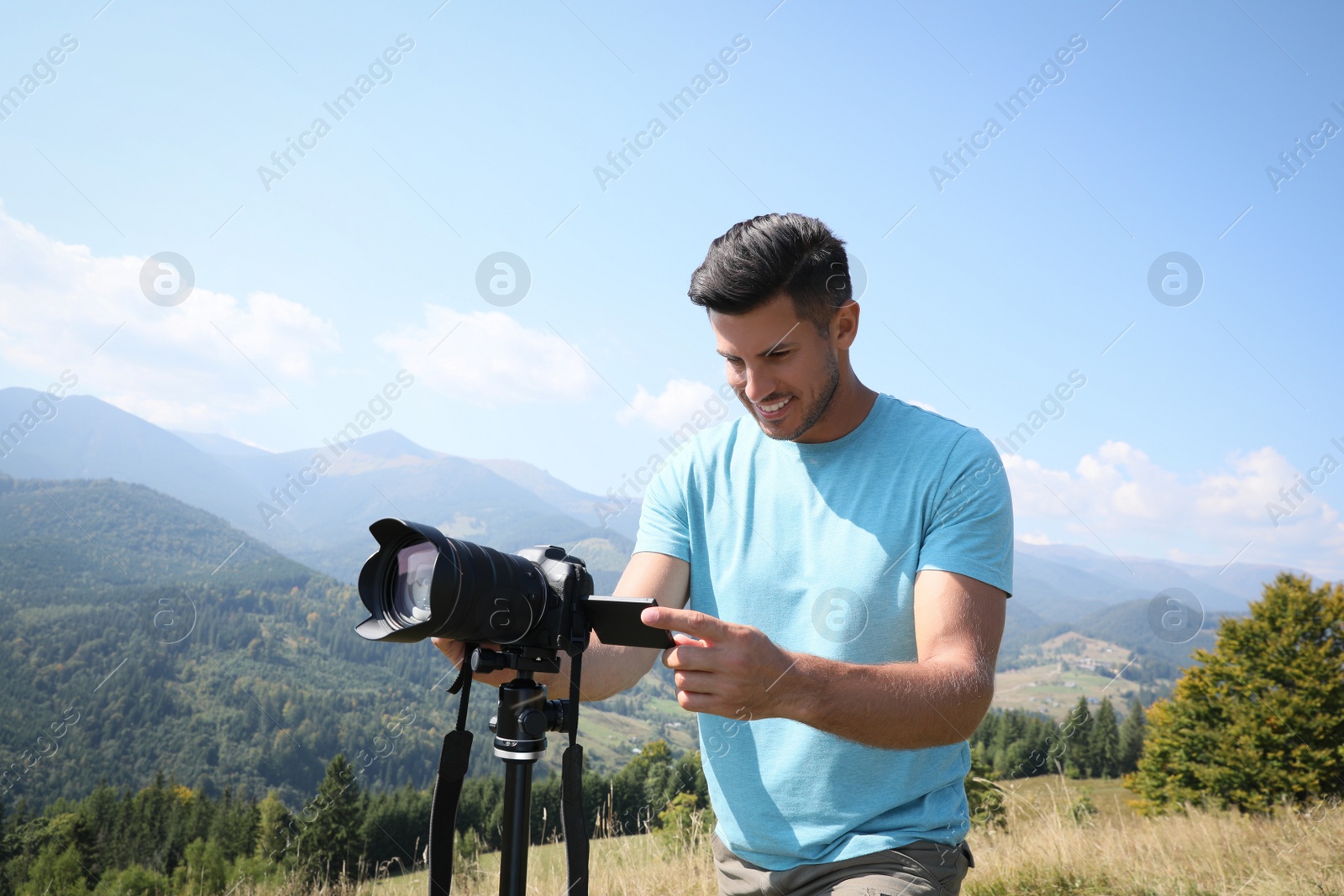 Photo of Professional photographer taking picture with modern camera in mountains