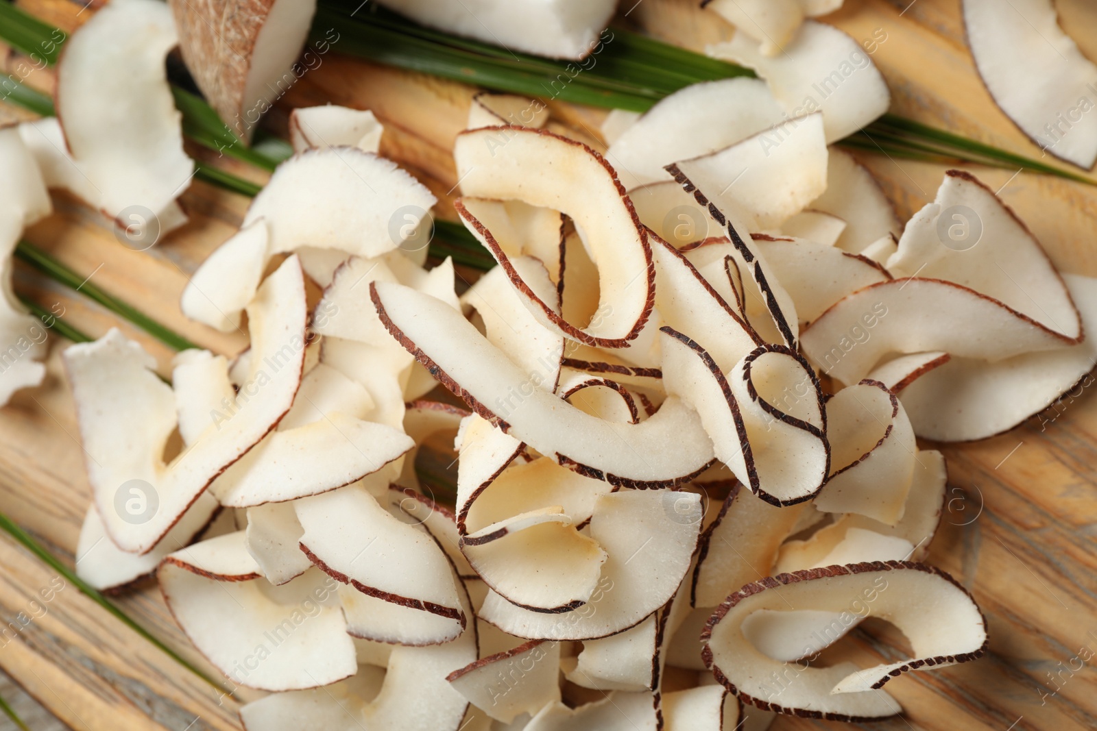 Photo of Pile of tasty coconut chips on wooden table