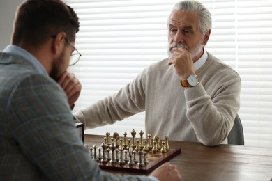 Photo of Men playing chess during tournament at table indoors
