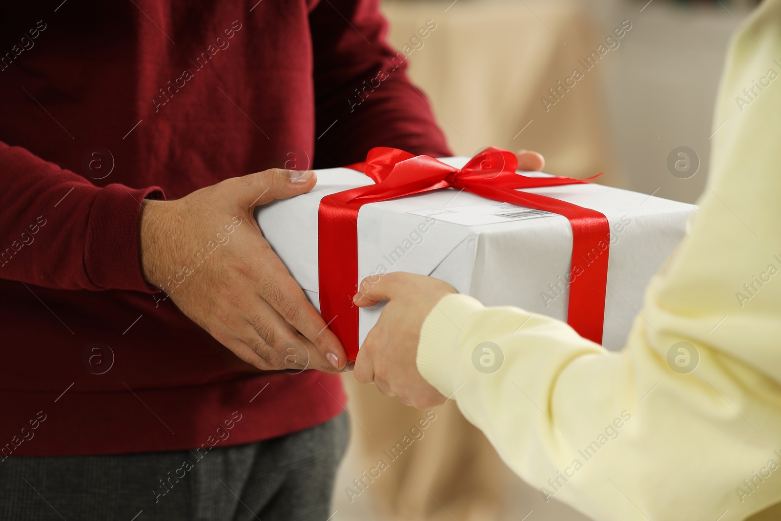 Photo of Man giving woman Christmas gift box received by mail indoors, closeup