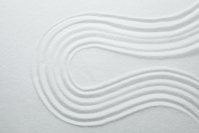 Photo of White sand with pattern as background, top view. Zen, meditation, harmony