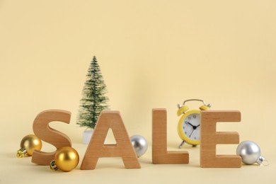 Photo of Word Sale made with wooden letters and Christmas decor on beige background