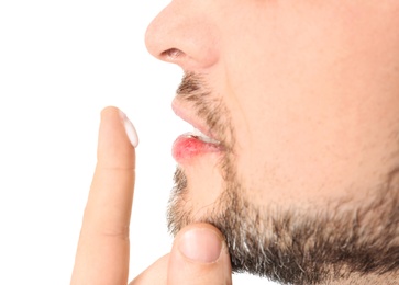 Photo of Man applying cream onto lips on white background, closeup