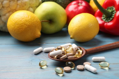 Photo of Dietary supplements. Spoon with different pills near food products on light blue wooden table, closeup