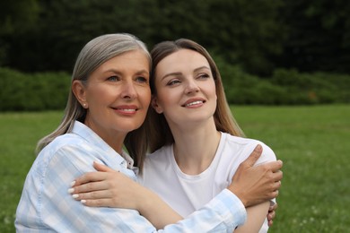 Happy mature mother and her daughter hugging in park