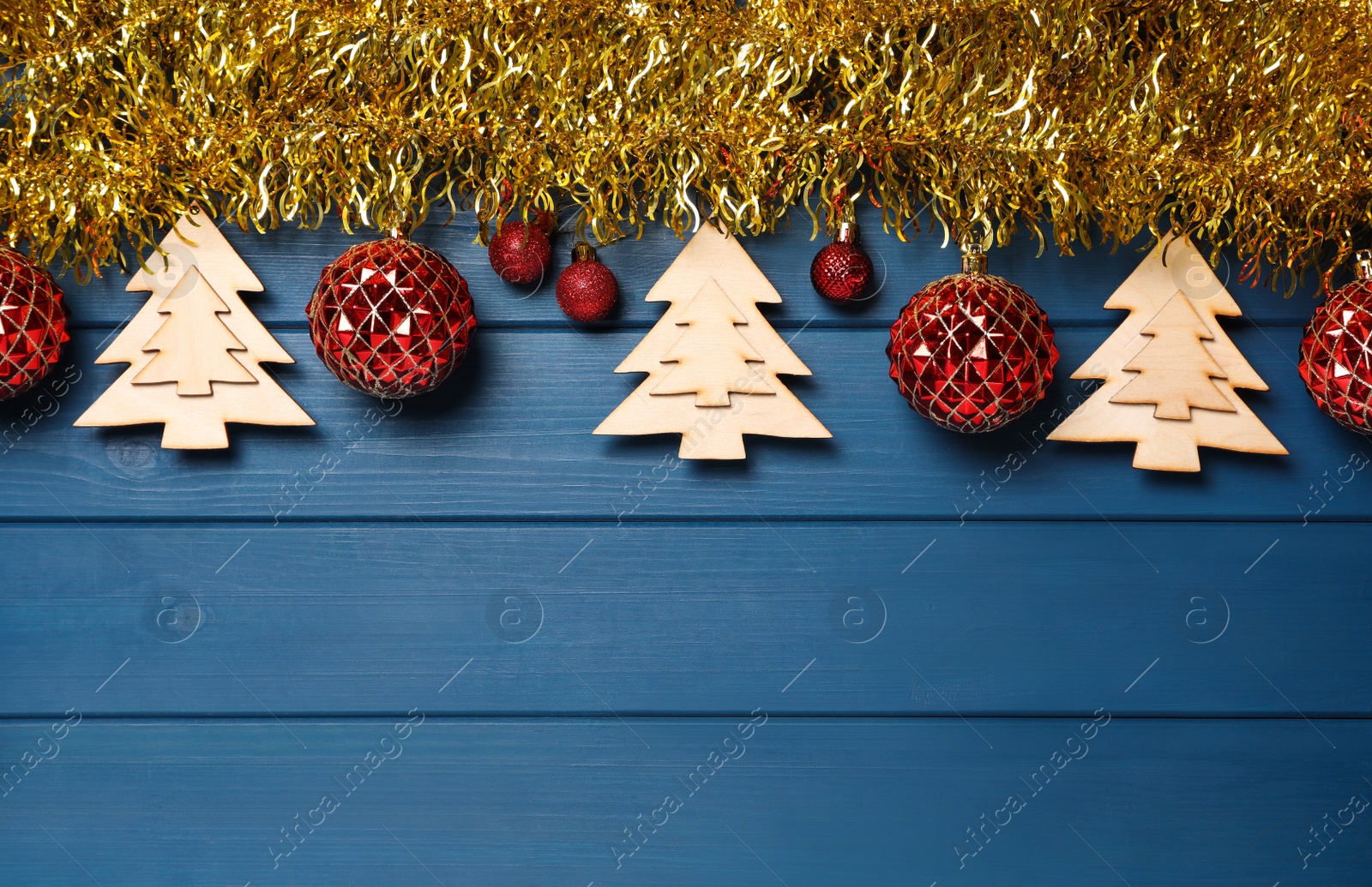 Photo of Bright tinsel and Christmas decor on blue wooden background, flat lay. Space for text