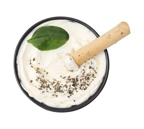 Photo of Bowl of delicious cream cheese with grissini stick, basil leaf and spices isolated on white, top view