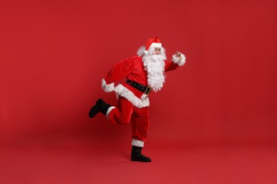 Photo of Merry Christmas. Santa Claus running on red background