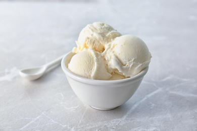 Photo of Bowl with tasty vanilla ice cream on light background
