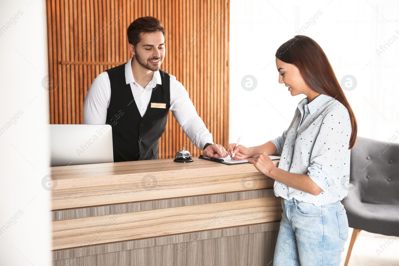 Photo of Receptionist registering client at desk in lobby