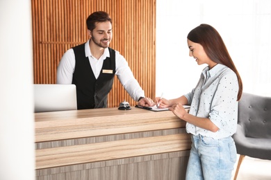 Photo of Receptionist registering client at desk in lobby