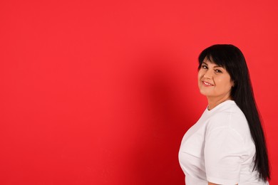 Photo of Beautiful overweight mature woman with charming smile on red background. Space for text