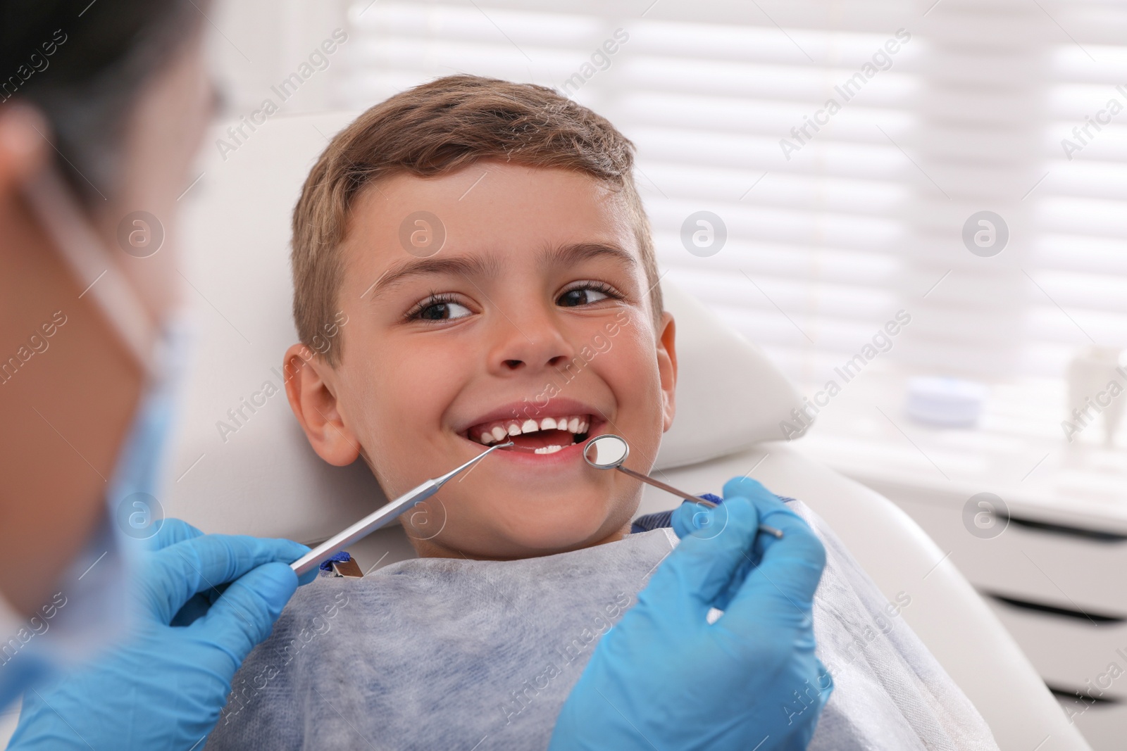 Photo of Dentist examining little boy's teeth in modern clinic