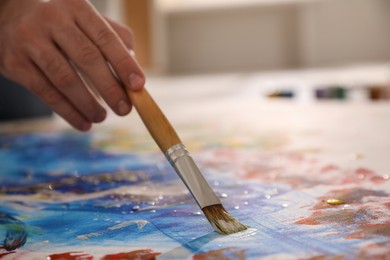 Photo of Man painting on canvas with brush, closeup. Young artist