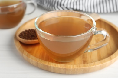 Photo of Glass cup of delicious buckwheat tea on white wooden table, closeup