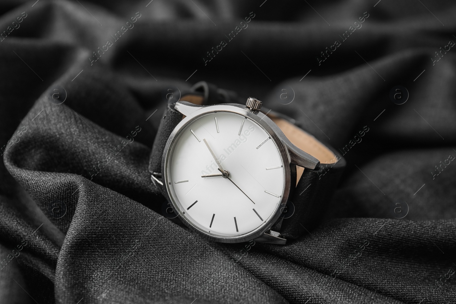 Photo of Stylish wrist watch on dark fabric. Fashion accessory