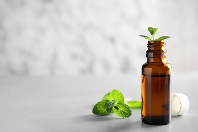 Photo of Bottle with mint essential oil on table