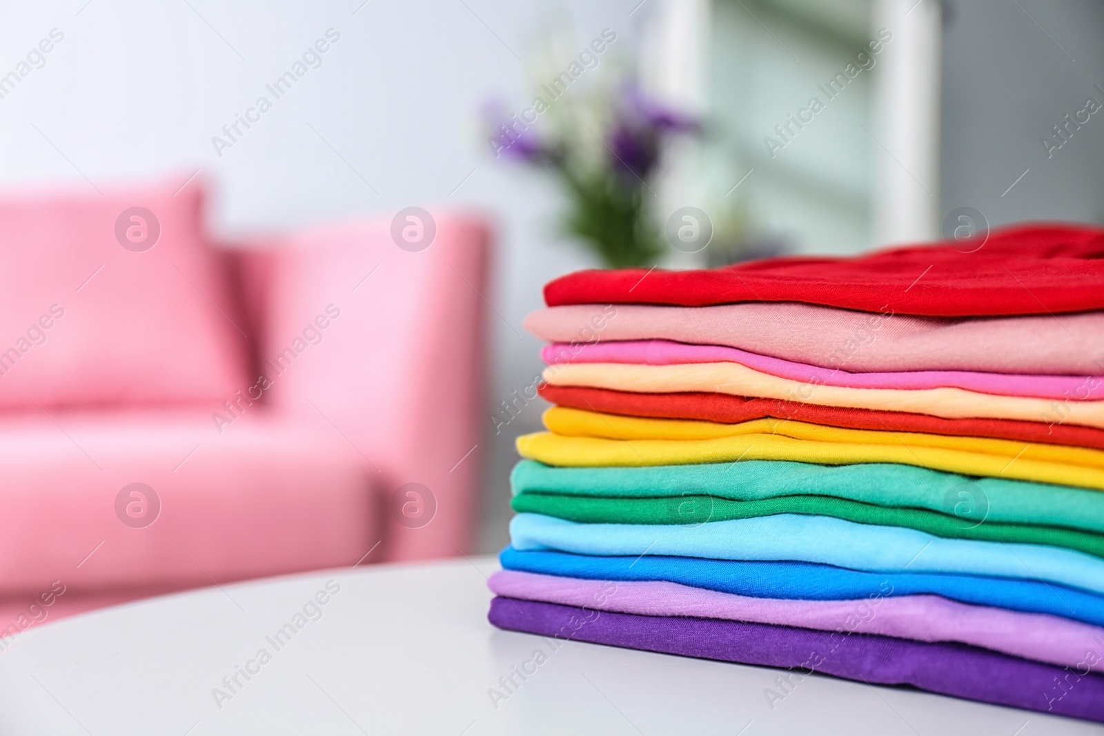 Photo of Stack of colorful t-shirts on table in living room