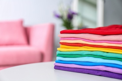 Photo of Stack of colorful t-shirts on table in living room